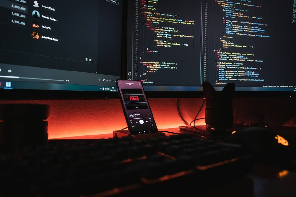 Two game developers reviewing C++ code together in a modern studio with game assets on screen